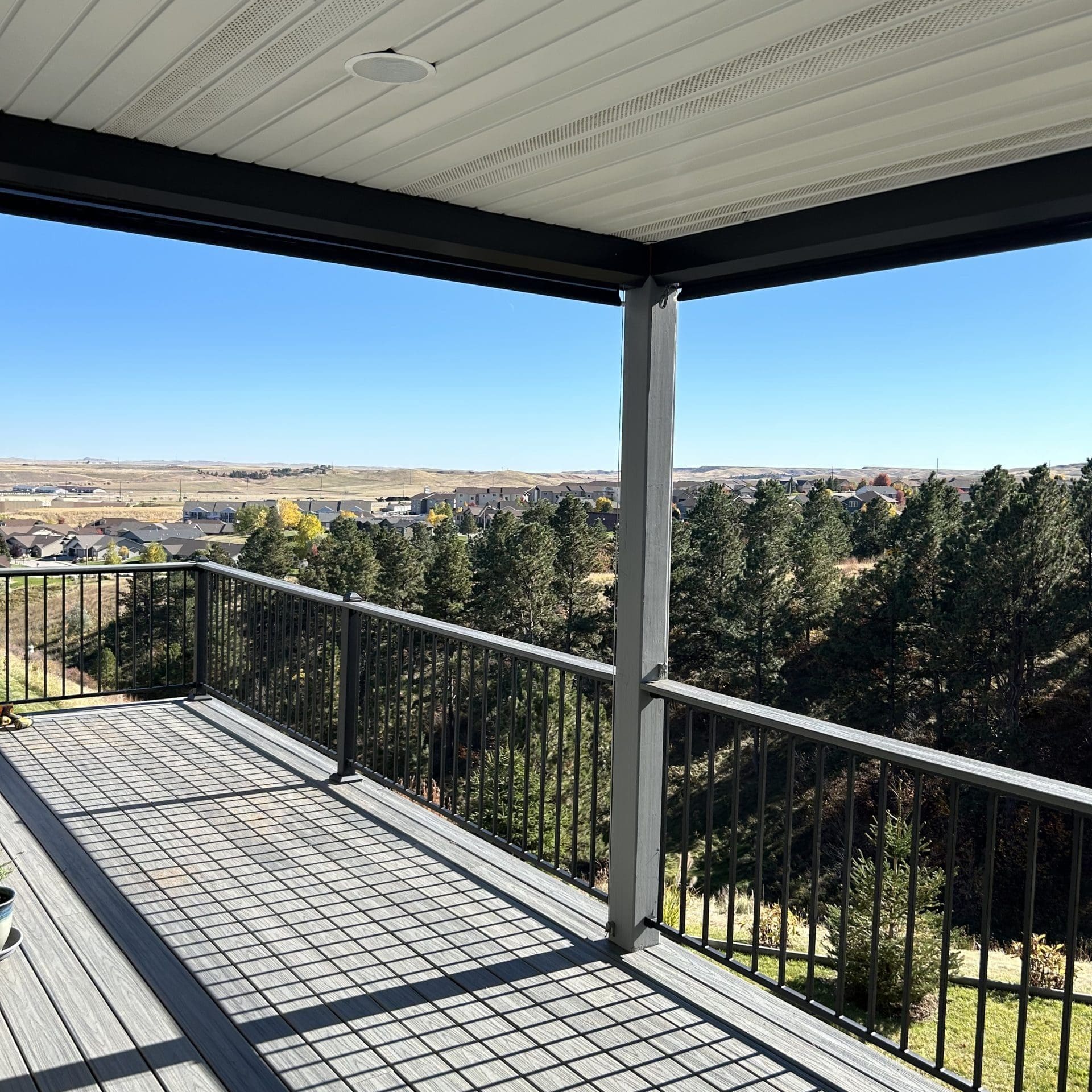 Gray Trex deck with metal railing and partially covered.